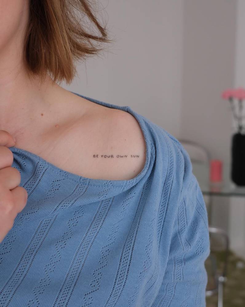 Healed "be your own sun" lettering tattoo located on the shoulder.