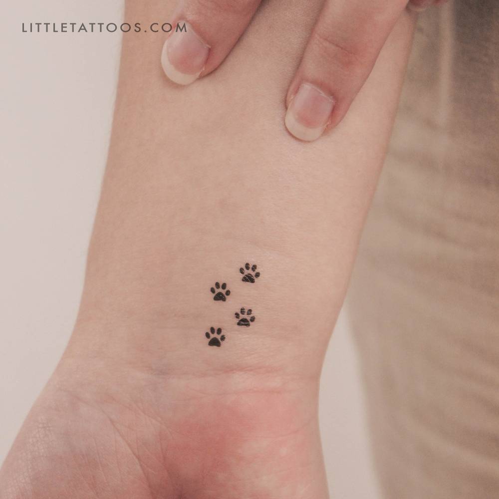 Minimalistic style four tiny paws temporary tattoo located on the wrist.