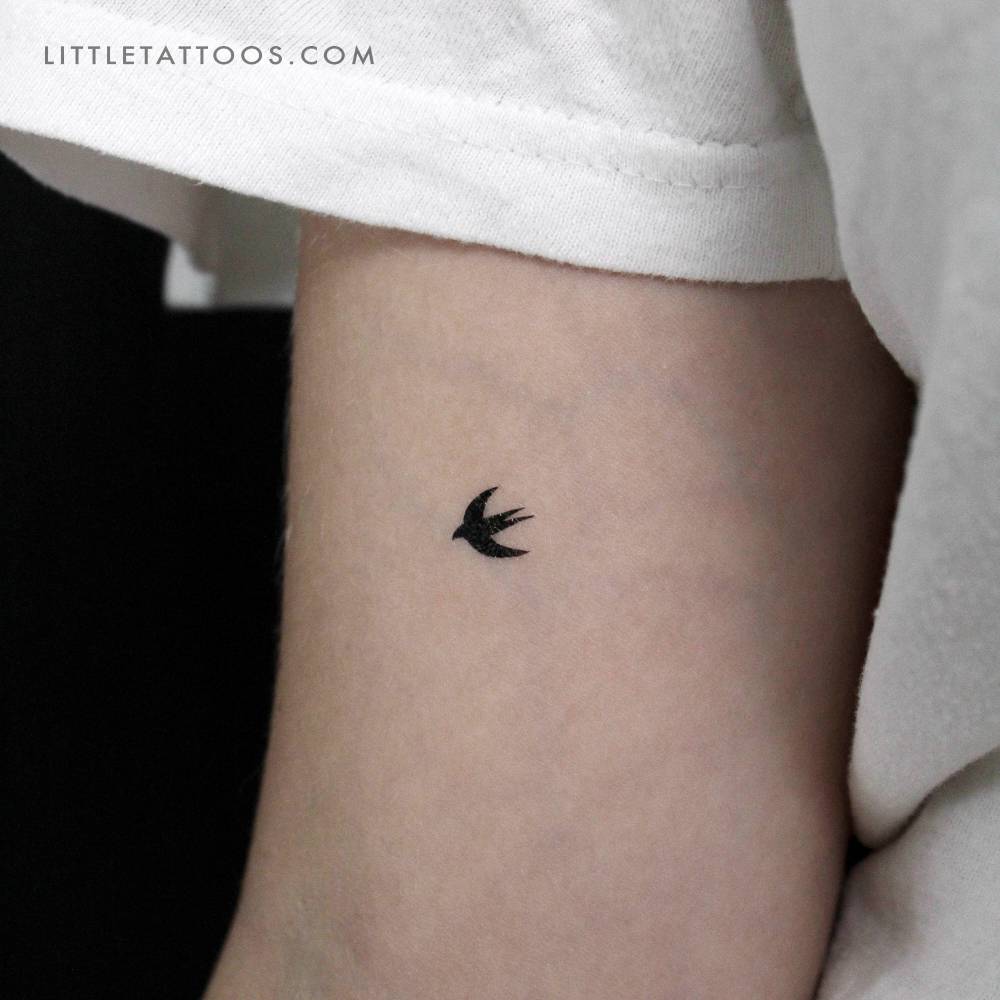 Tiny minimalistic swallow temporary tattoo located on the inner arm.
