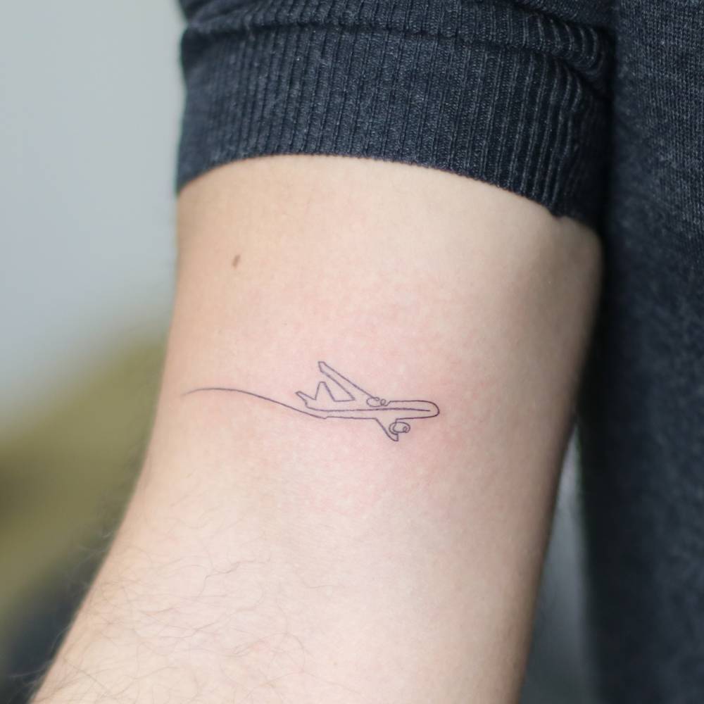 One line airplane tattoo located on the bicep.