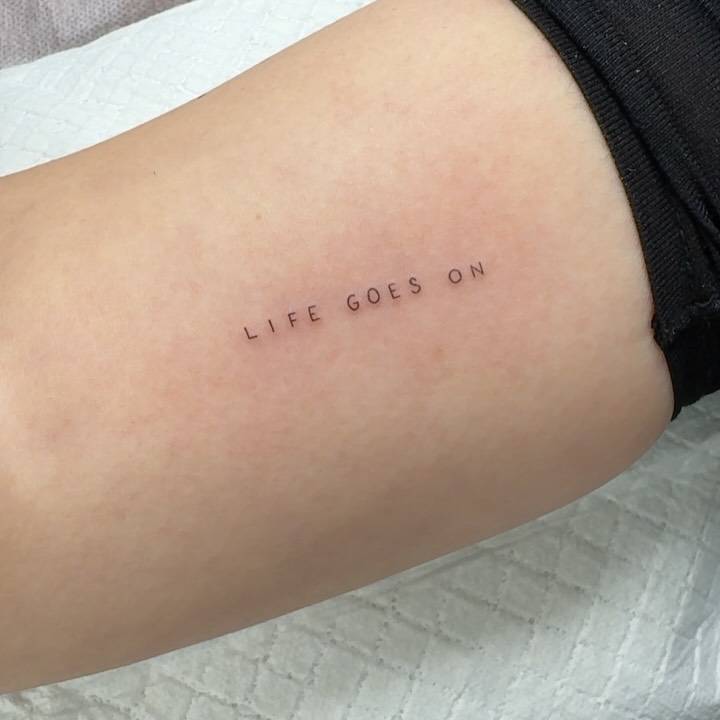 "Life goes on" lettering tattoo located on the inner arm.