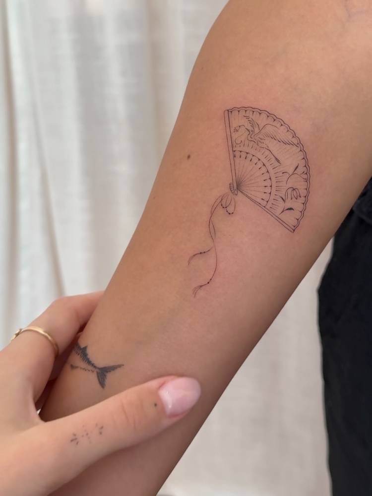 Fine line style hand fan tattoo done on the inner forearm.