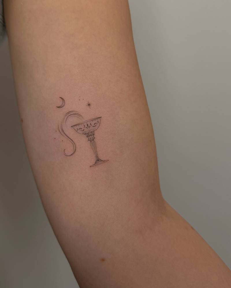 Fine line style chalice tattoo located on the inner arm.