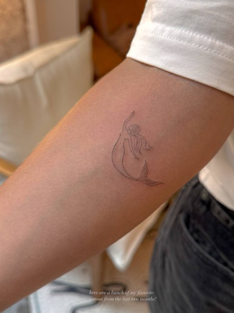 Mermaid tattoo in fine line style located on the inner forearm.