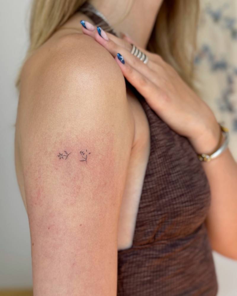 Tiny minimalistic flowers tattooed on the upper arm.