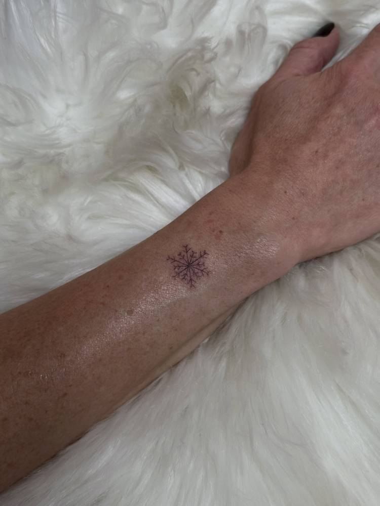Little snowflake tattoo located on the wrist.