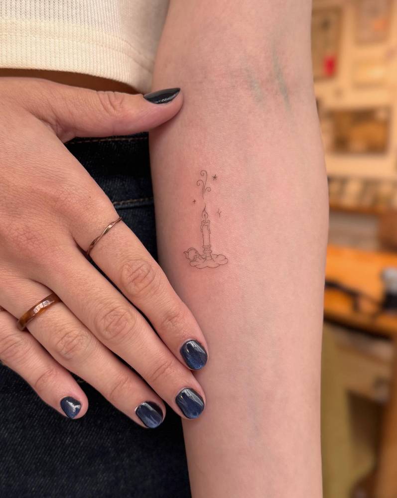 Candle tattoo located on the inner forearm, done in fine line style.