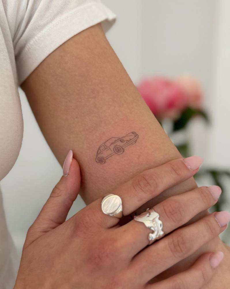 Porsche tattoo located on the upper arm, done in fine line style.