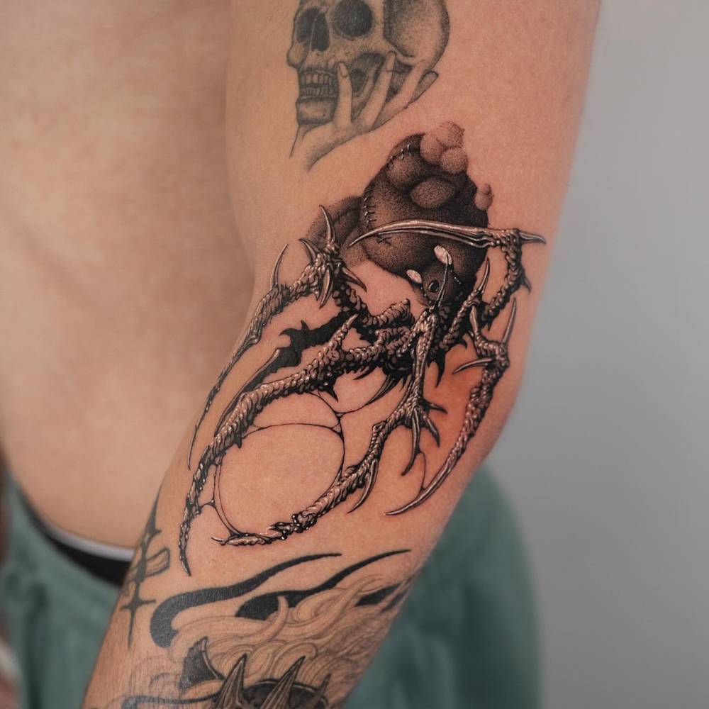 Comic style monster teddy bear tattoo located on the elbow.