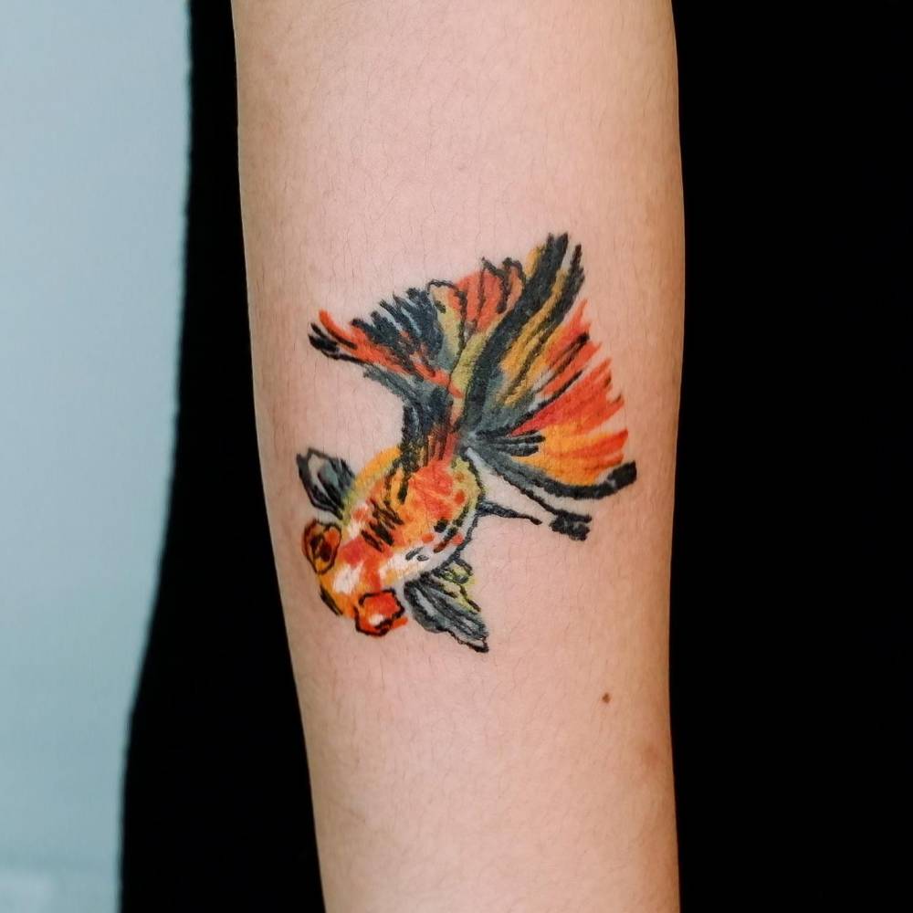 Goldfish tattoo located on the forearm, watercolor style.