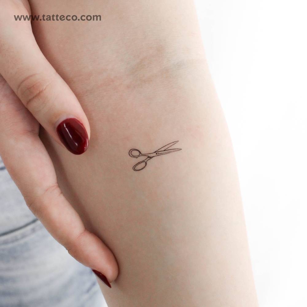 Scissors temporary tattoo in fine line style located on the inner forearm.