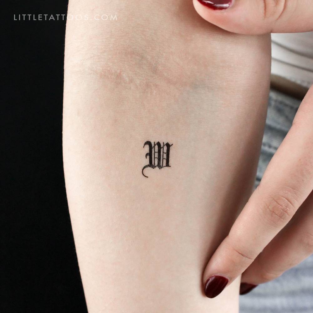 Gothic font "W" letter temporary tattoo located on the inner forearm.