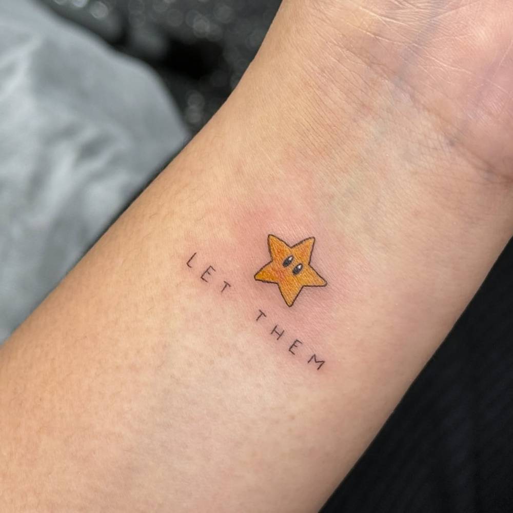 Mario's Super Star and "let them" tattoo located on the wrist.