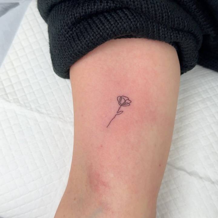 One line flower tattoo located on the inner arm.