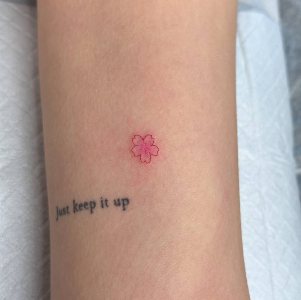 Tiny minimalistic cherry blossom tattoo located on the inner arm.