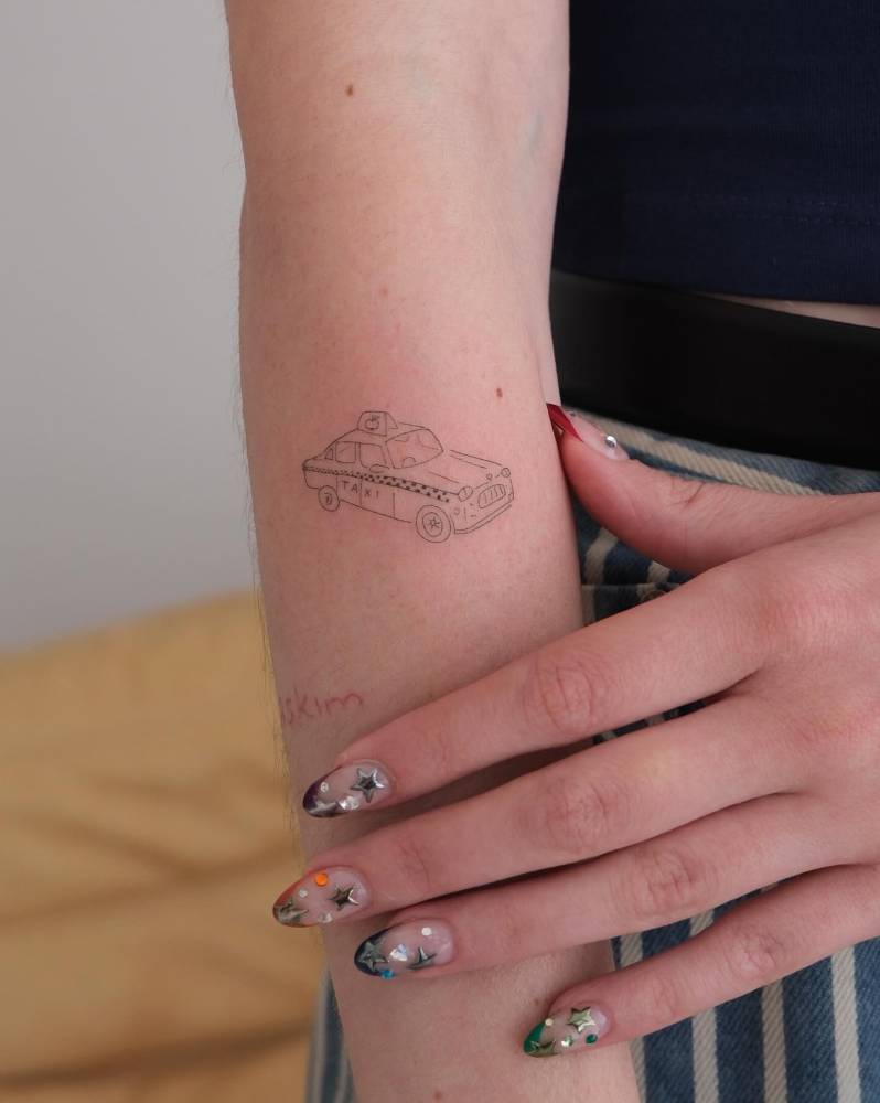 Fine line style taxi tattoo located on the forearm.