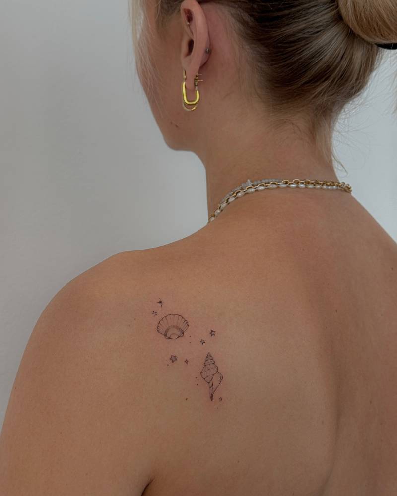Scallop and tulip shells tattooed on the shoulder blade.