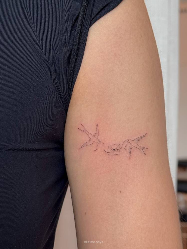 Swallows and love letter tattoo located on the upper arm.