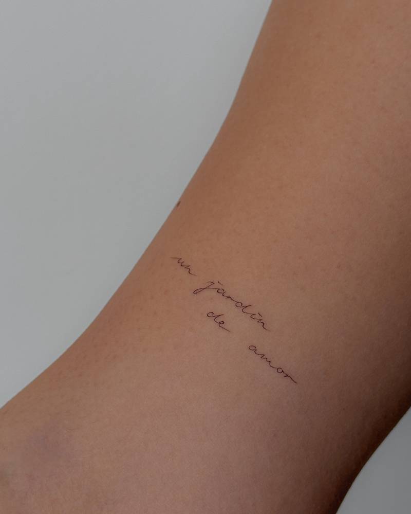 "Un jardin de amor" lettering tattoo located on the bicep.