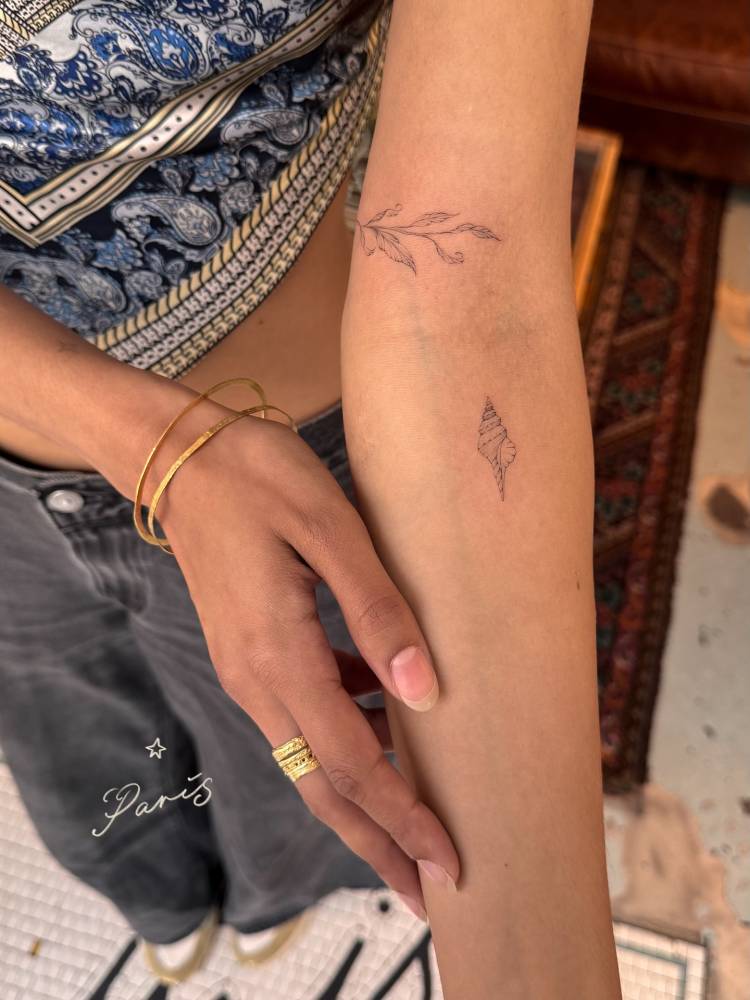 Tulip shell tattoo in fine line style located on the inner forearm.