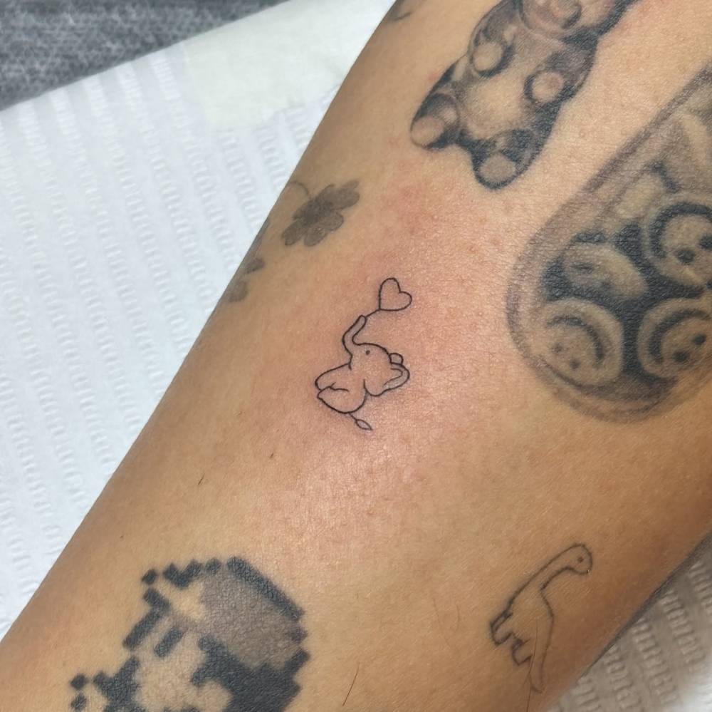 Tiny elephant and heart tattoo located on the shin.