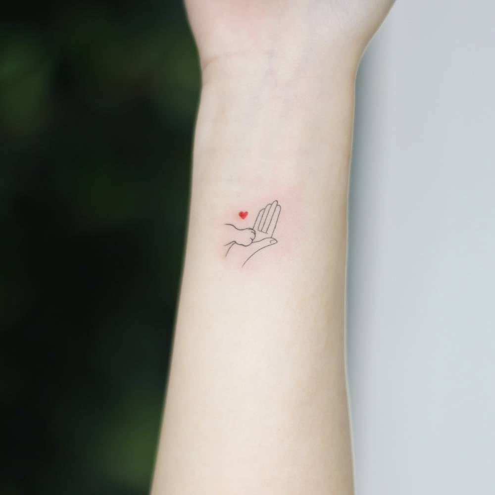 Dog high five tattoo located on the wrist, minimalistic style.