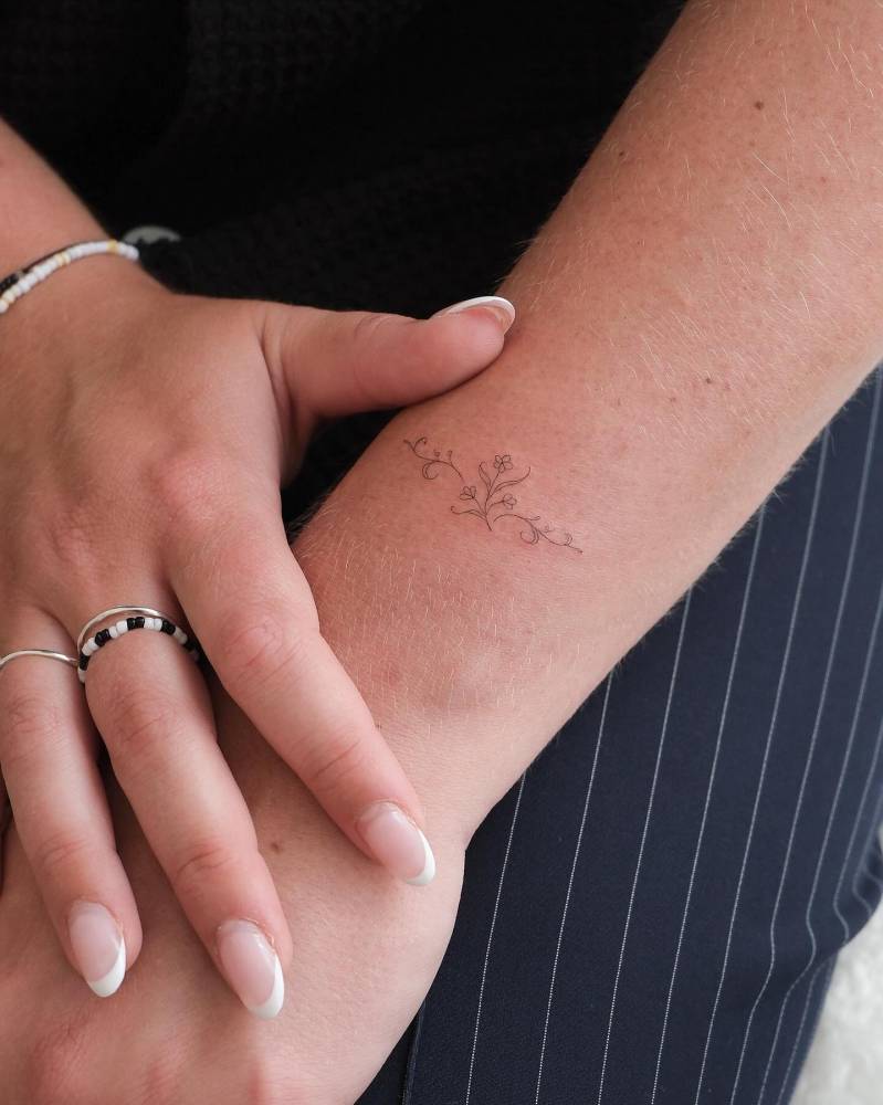 Fine line style flowers tattooed on the wrist.