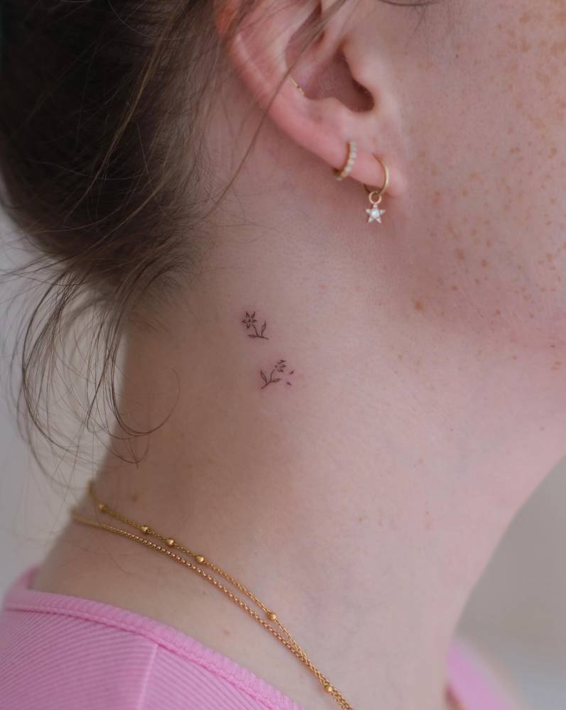 Tiny minimalistic flowers tattooed on the neck.
