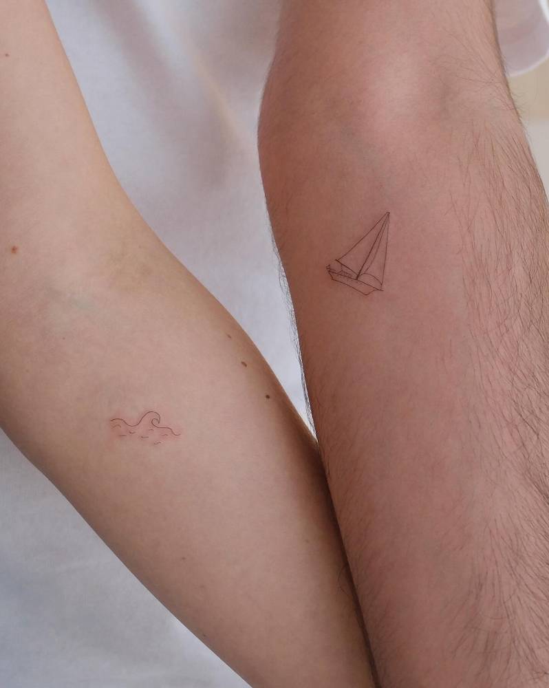 Matching wave and sailboat tattoos for couple.