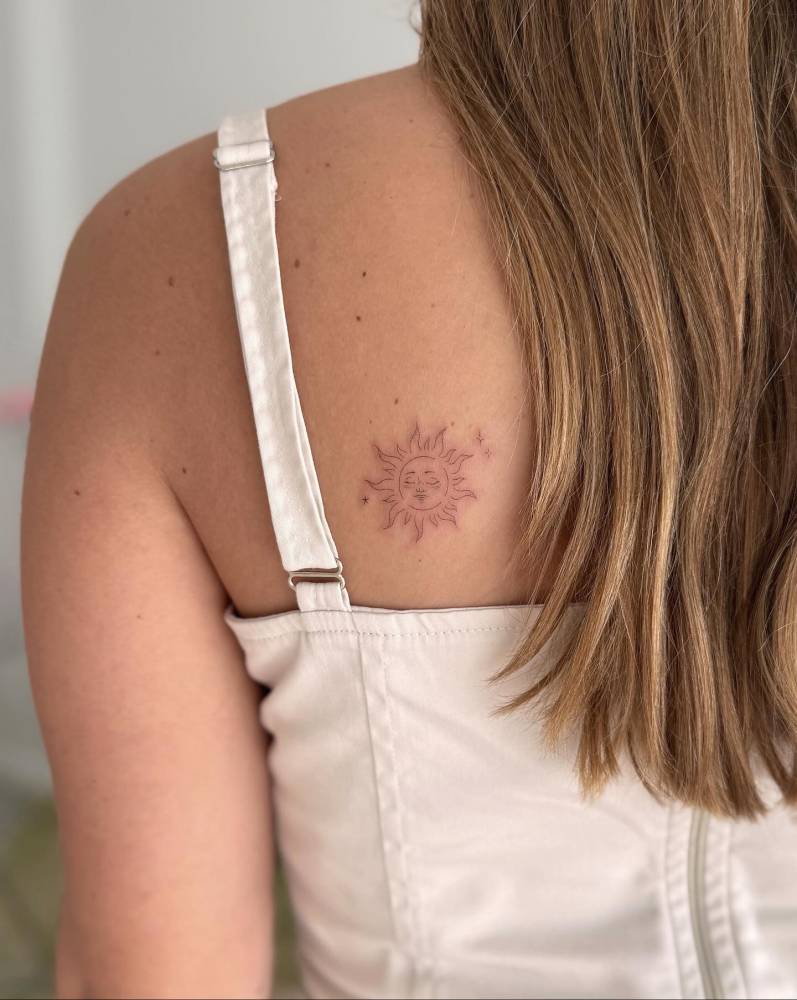 Inti sun tattoo in fine line style located on the shoulder blade.