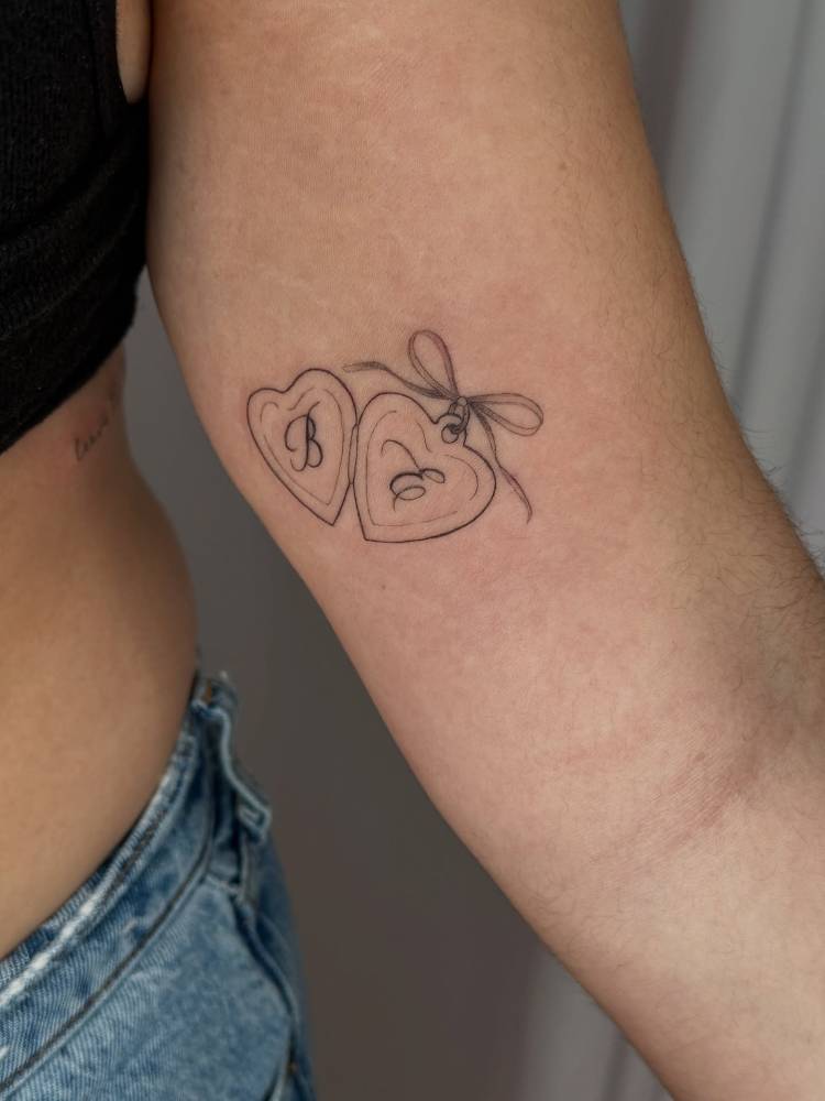 Heart pendant tattoo illustrative style located on the inner arm.