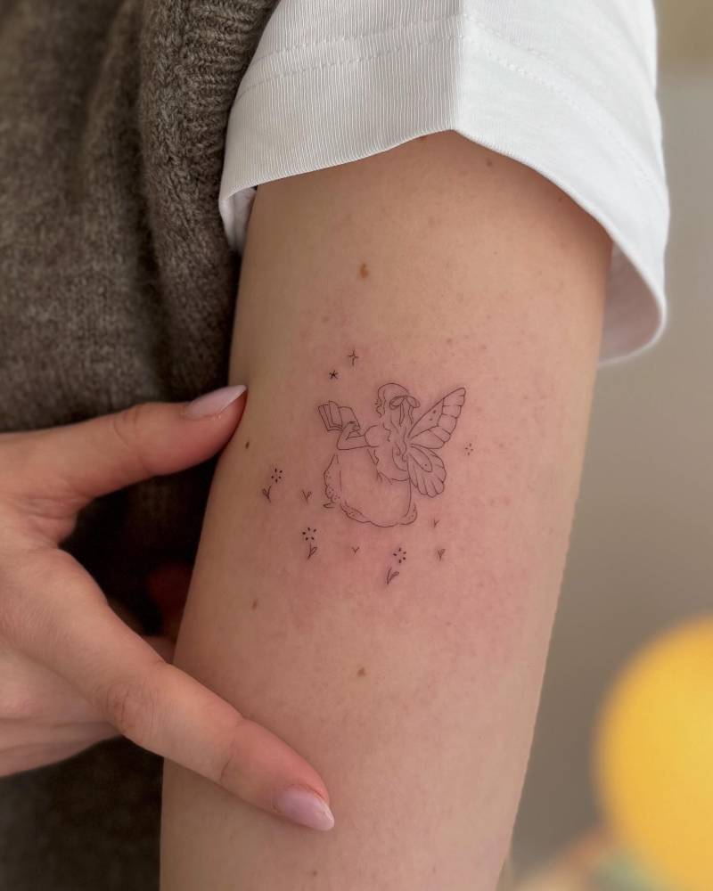 Fine line style fairy tattoo placed on the upper arm.