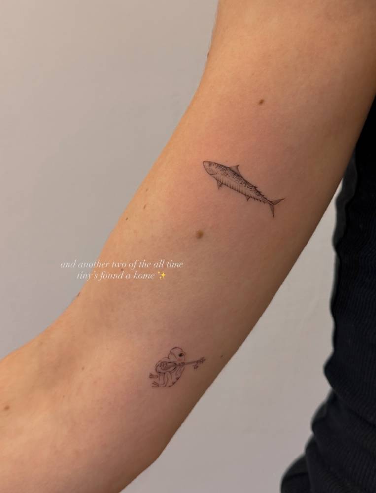 Illustrative style mackerel fish tattooed on the inner arm.