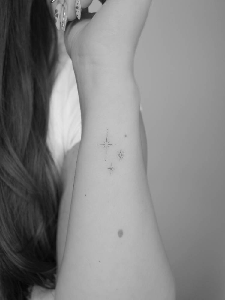 Sparkling stars tattoo in minimalistic style located on the wrist.