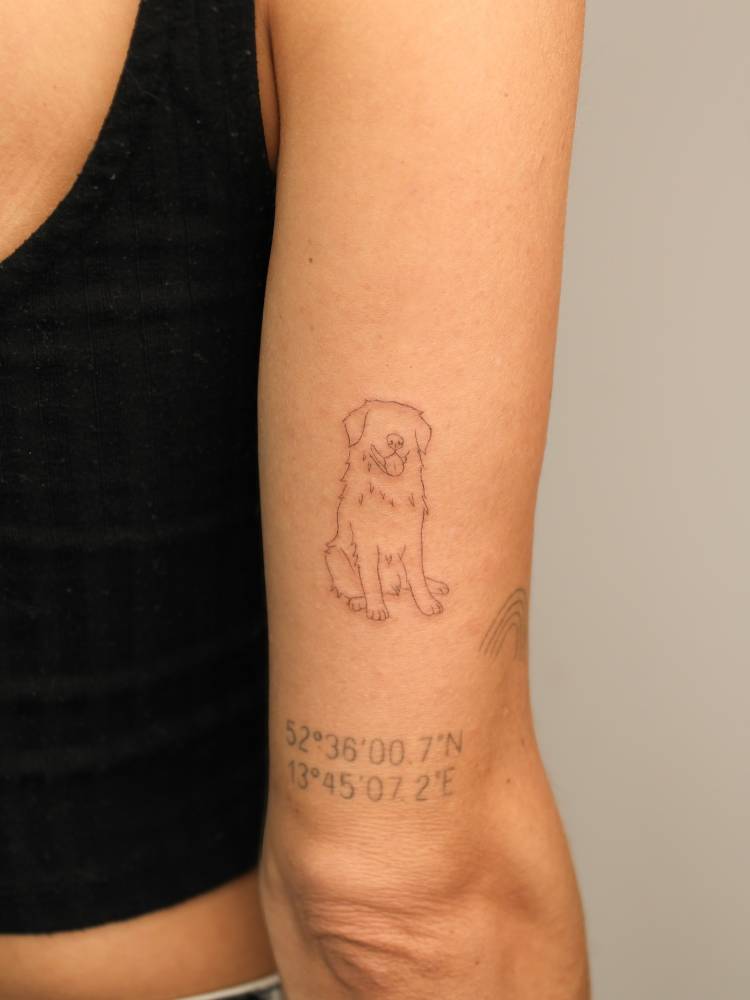 Golden retriever tattoo in fine line style located on the tricep.