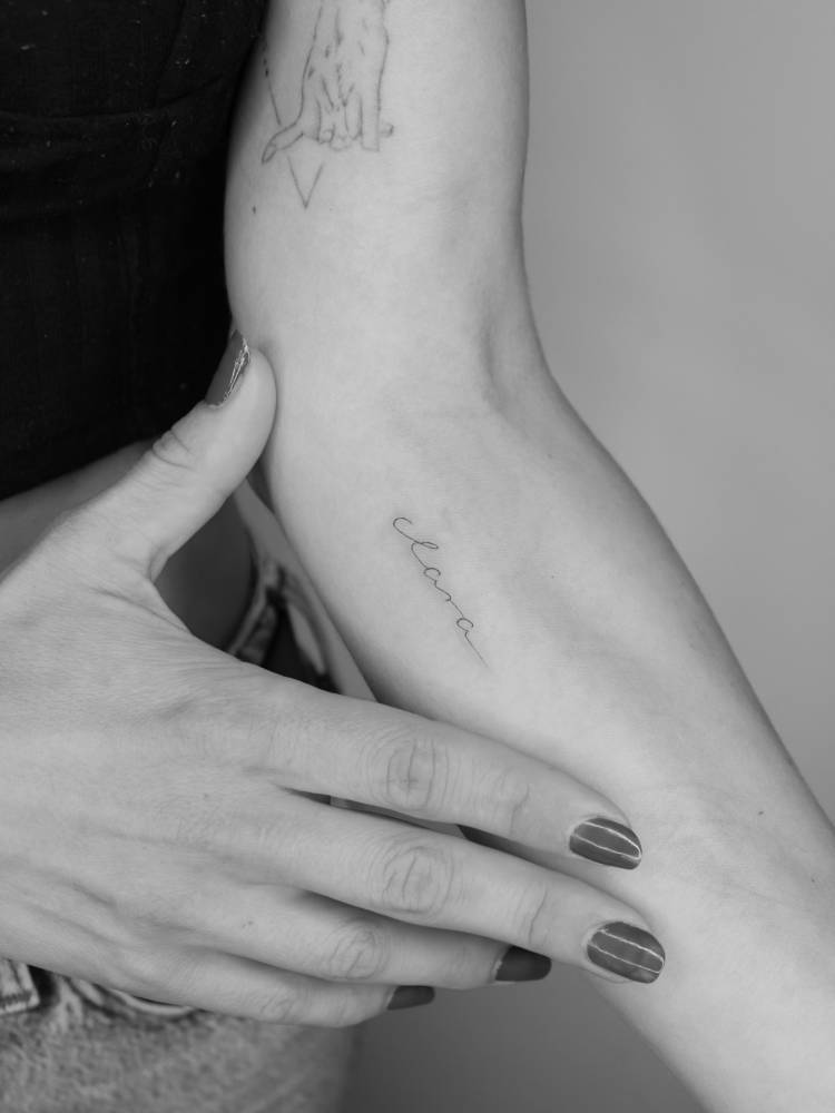 Handwritten font name "Clara" tattooed on the inner forearm.