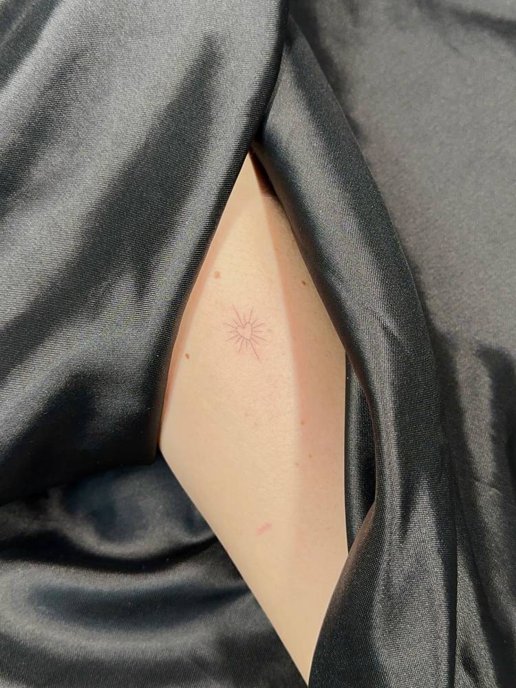 Shining heart tattoo in fine line located on the sternum.