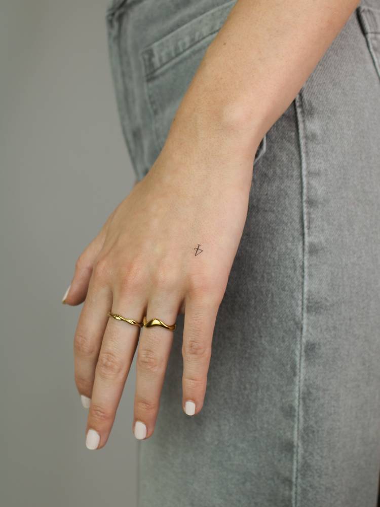 Tiny minimalistic tattoo of the number "4" located on the hand.