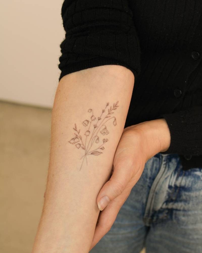 Flower bouquet tattoo located on the inner forearm, fine line style.