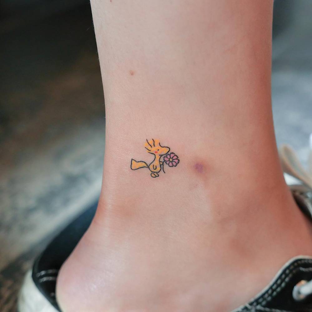 Cartoon style Woodstock tattoo located on the ankle.