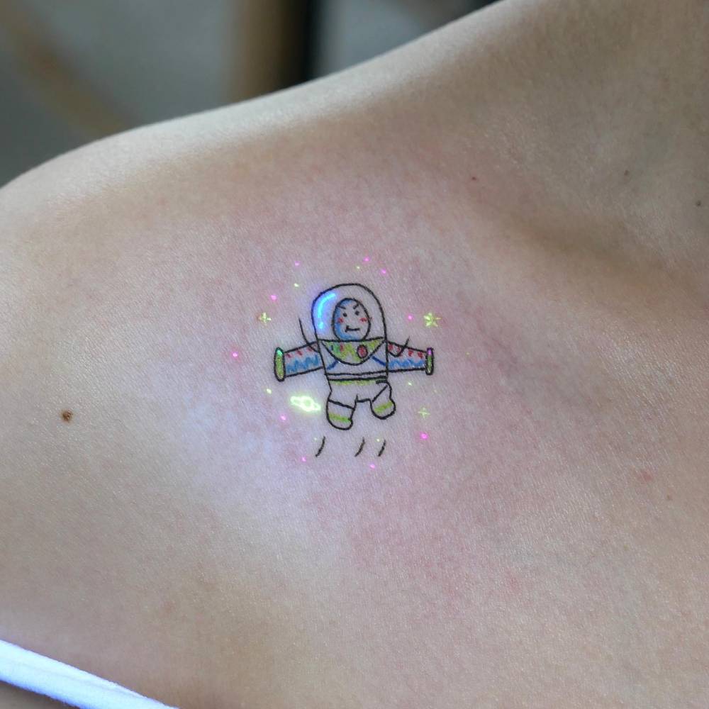Cartoon style Buzz Lightyear tattoo located on the collarbone.