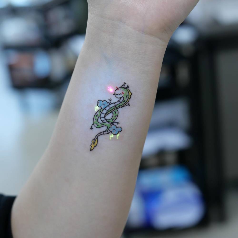 UV ink dragon tattoo in cartoon style located on the wrist.