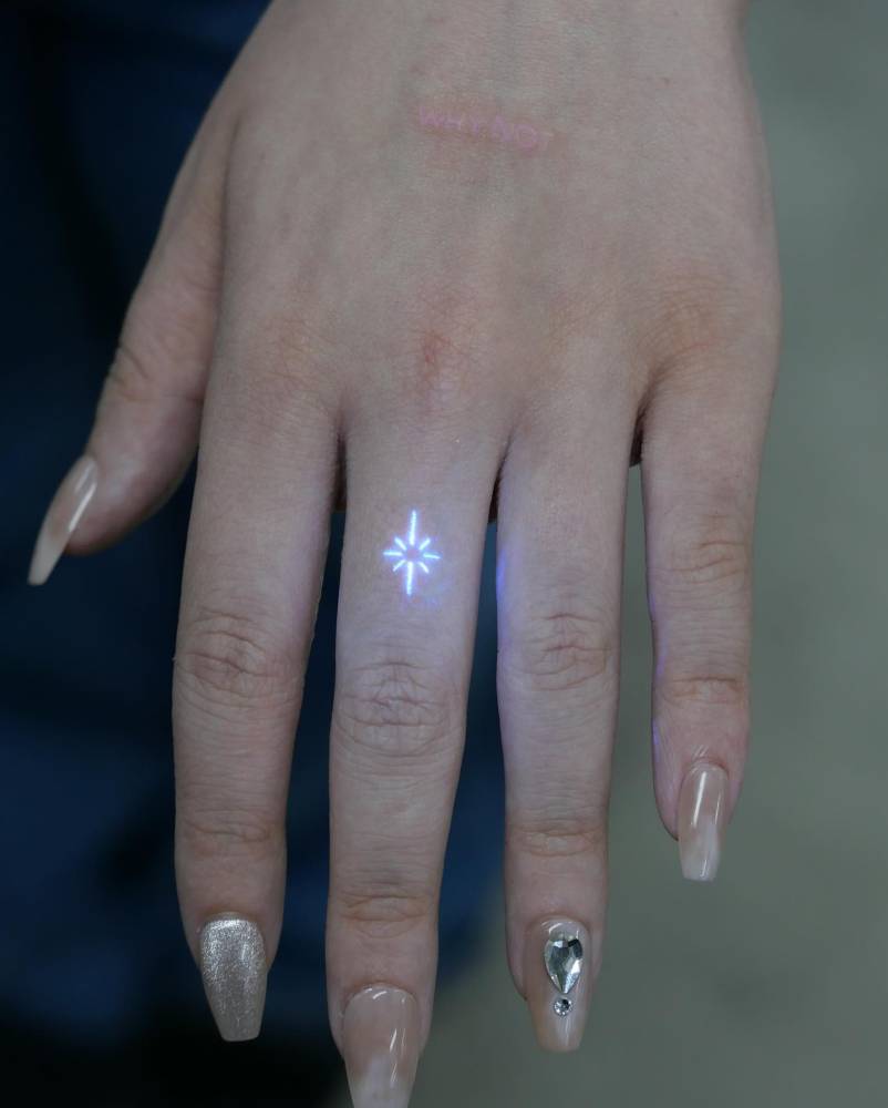 Minimalistic north star tattoo in UV ink located on the finger.