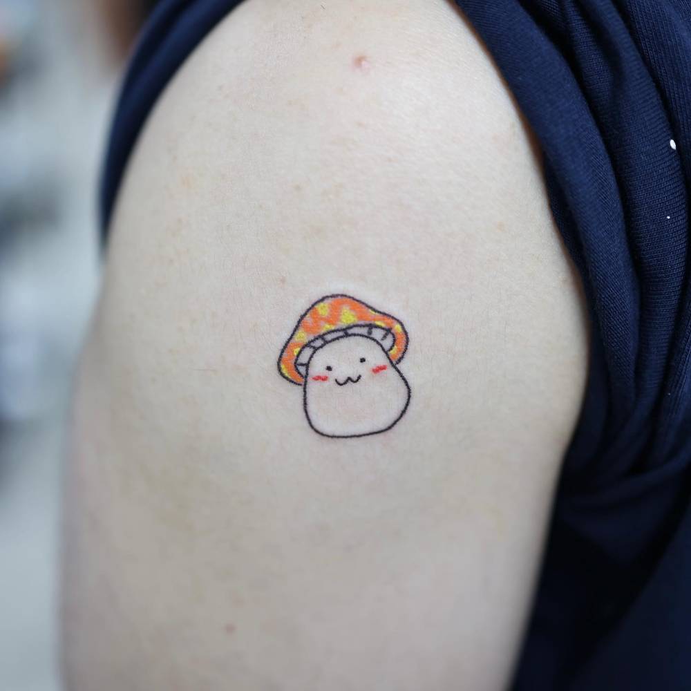 Cartoony mushroom tattoo located on the shoulder.