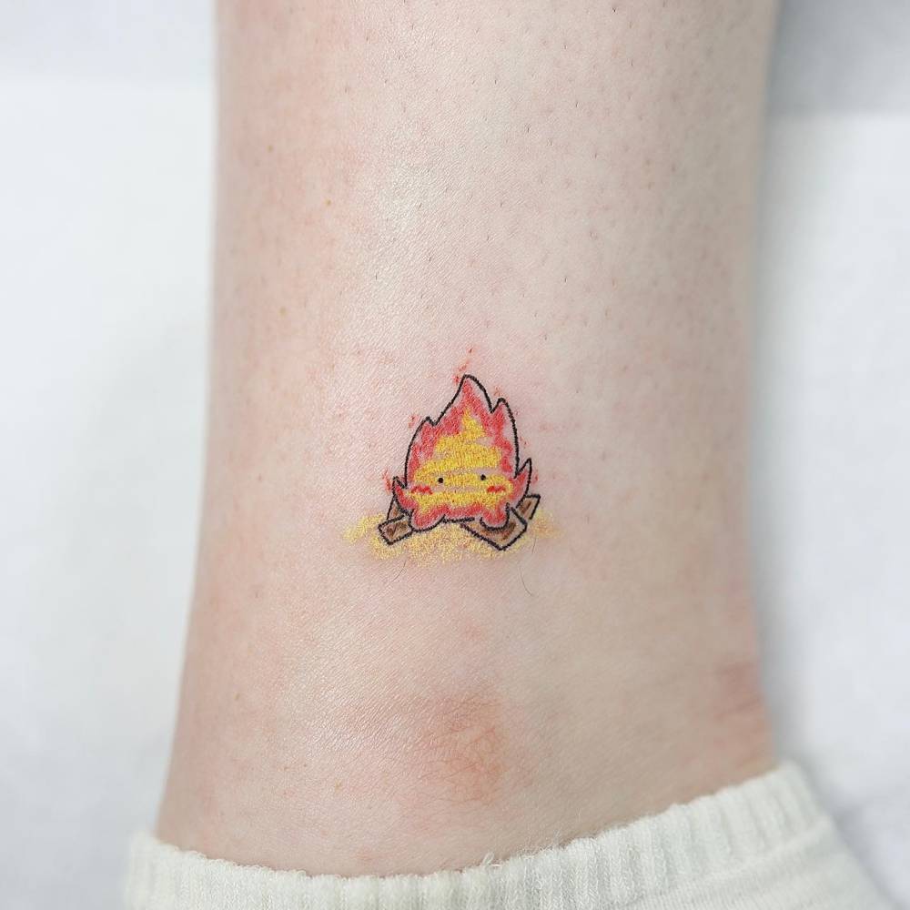 Calcifer bonfire tattoo located on the ankle, cartoon style.