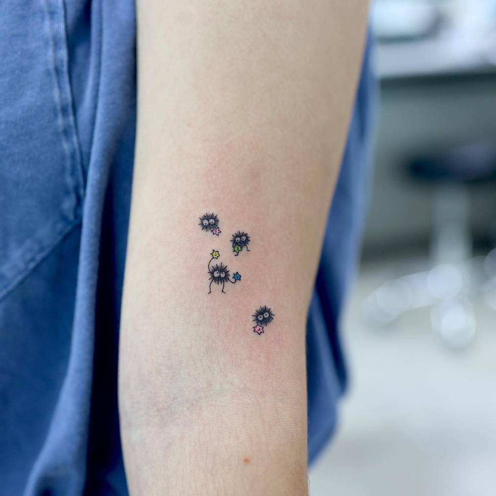 Little Soot Sprites tattooed on the upper arm, cartoon style.