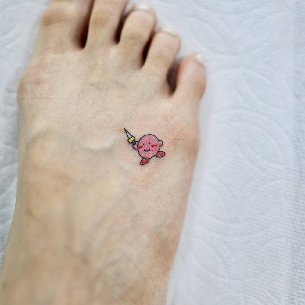 Cute Kirby tattoo in cartoon style located on the foot.