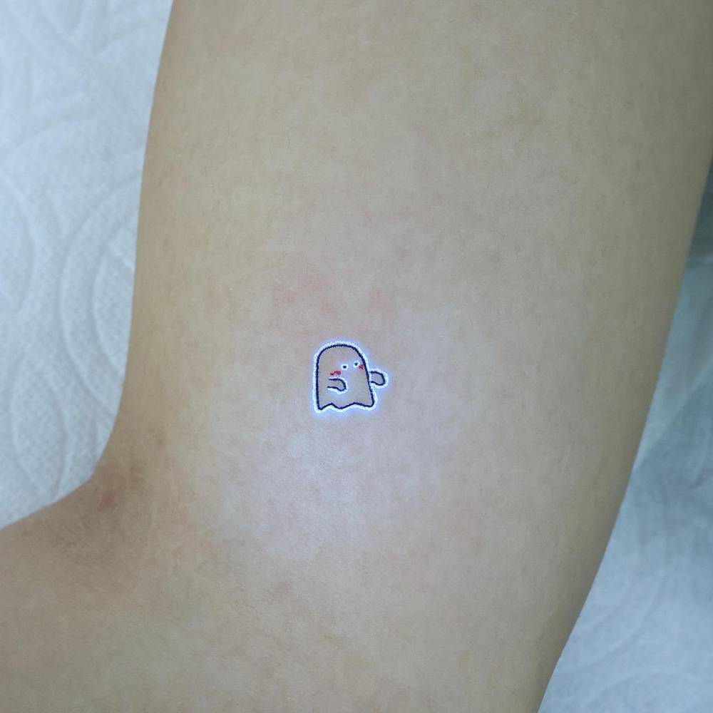 Ignorant style UV ink ghost tattoo located on the inner arm.