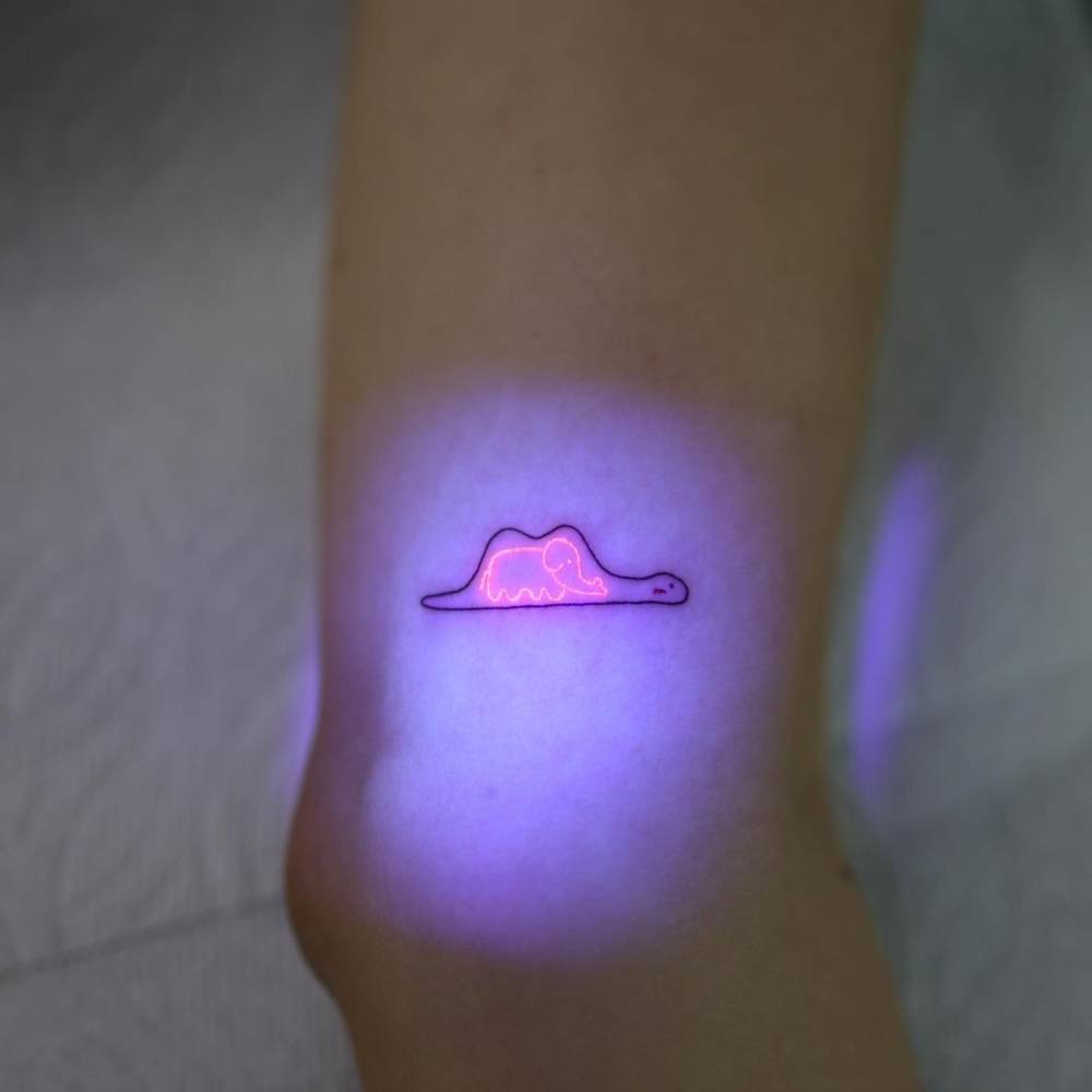 UV ink elephant inside boa tattoo located on the inner arm.