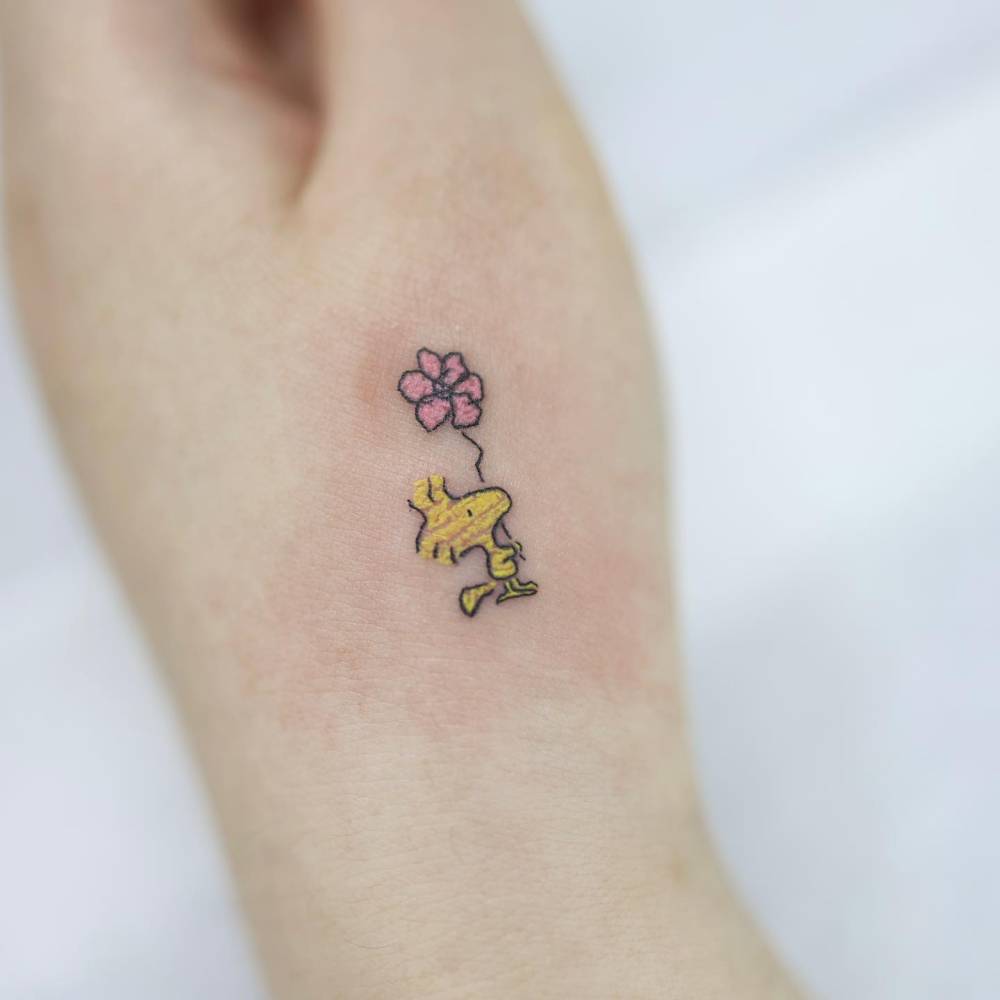 Cartoon style Woodstock tattoo located on the hand.